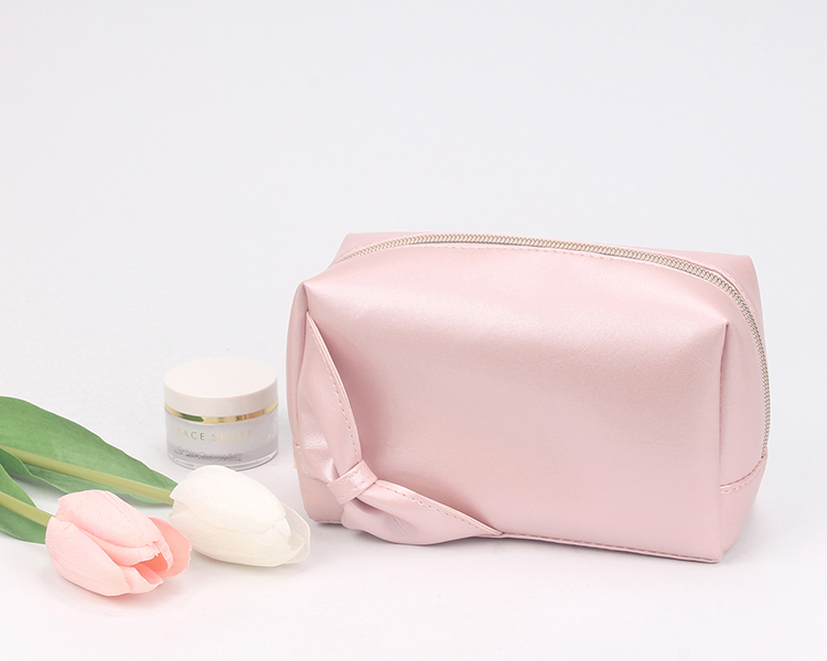Soft pink satin cosmetic pouch with side knot decoration, gold metal zipper, portable travel makeup bag