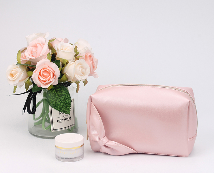 Soft pink satin cosmetic pouch with side knot decoration, gold metal zipper, portable travel makeup bag